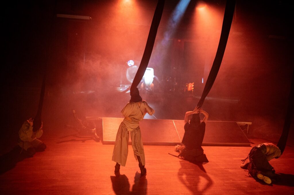 Sorry we didn't respond earlier stage image with masked performers and smoke